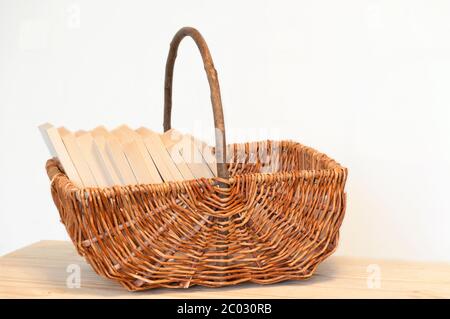 Korbkorb mit Büchern auf einem Holztisch. Stockfoto