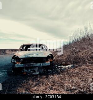 Verlassene Auto auf der Seite der Straße mit Gras Rand, Pfützen und Himmel - "Ende der Straße" Stockfoto