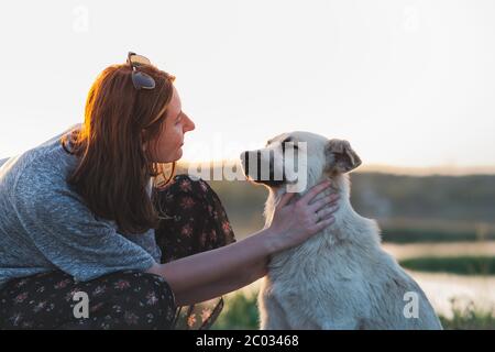 Frau Haustiere Hund in der Natur bei Sonnenuntergang. Beziehung zwischen Mensch und Tier, Kommunikation und Interaktion Stockfoto