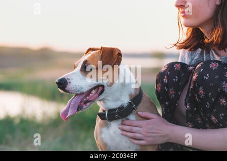 Glücklicher Hund mit geschlossenen Augen in den weiblichen Händen, Sommersaison. Frau umarmt ihren staffordshire Terrier Hund bei einem Spaziergang im Freien Stockfoto