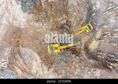 Der Bagger gräbt Ton aus der Grube des Gebäudes, die restlichen Pfähle, Luftaufnahme von oben Stockfoto