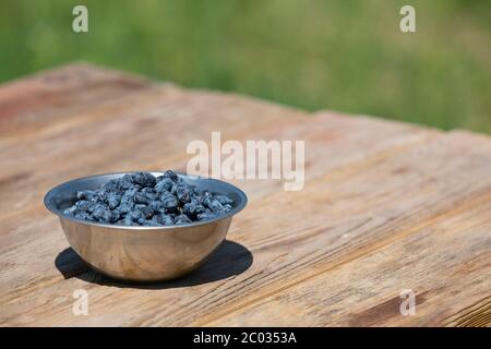 Blaue Geißelbeeren in Schale auf Holztisch Hintergrund mit Copyspace Stockfoto