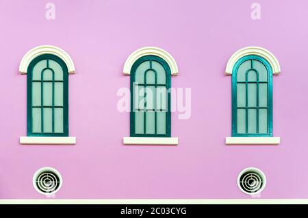 Drei grüne Bogenfenster an rosa Wand Stockfoto