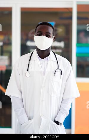 Afrikanische Arzt tragen Gesichtsmaske und hält Stethoskop Stockfoto