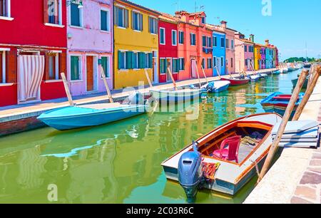 Blick auf den Kanal mit vertäuten Motorbooten und bunten Häusern in Burano in Venedig, Italien - Italienische Ansicht Stockfoto