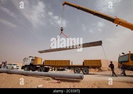 Ein Kran hebt Rohre an, die für ein Löschwassersystem in einer neuen Ölanlage in der Wüste Sahara verwendet werden. Stockfoto