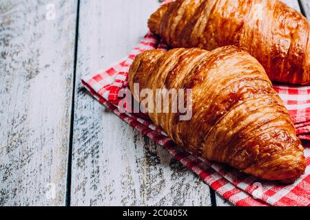 Frisch gebackene Croissants auf weißem Holztisch Hintergrund. Draufsicht, Kopierbereich. Konzept für das morgendliche Essen Stockfoto