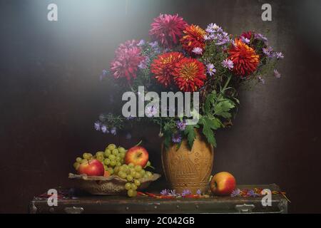 Die Trauben, die Äpfel und das Bouquet aus cinniya und die Aster, das herbstliche Stillleben Stockfoto