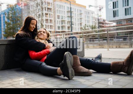 Happy Best Friends Umarmen Und Sitzen Auf Dem Boden In Der Stadt Stockfoto