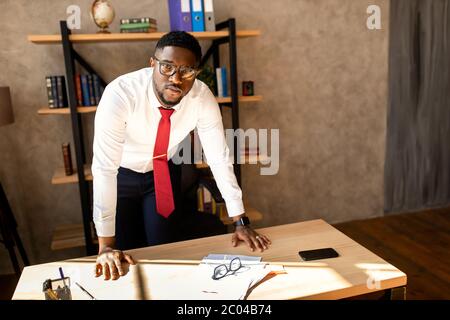 Schöner afroamerikanischer Geschäftsmann in weißem Hemd, der in seinem Büro steht Stockfoto