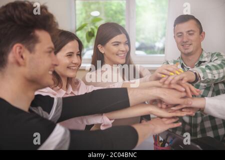 Einheit, Leistung, Konzept. 7/8 Schuß einer Gruppe Studenten lachen, ihre Hände zusammen. Fröhlicher junger peoople mit s Stockfoto