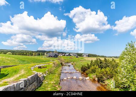 Sonniger Sommertag in Jizerka Bergdorf. Jizerka, grüne Wiesen und blauer Himmel mit weißen Wolken, Isergebirge, Tschechische Republik. Stockfoto