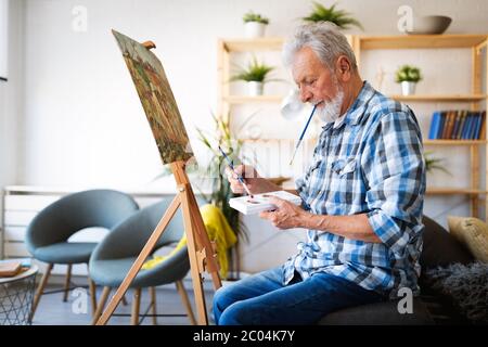 Glücklich Rentner Mann Malerei auf Leinwand für Spaß zu Hause Stockfoto