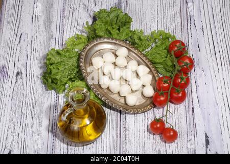 Mozzarella, Blätter von grünem Salat, Tomaten und Olivenöl Stockfoto