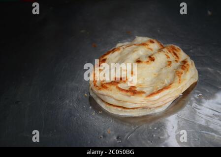 Weicher Fokus von Roti Canai oder Roti, das Mehl von Roti Maker mit Öl einstrebt. Indische traditionelle Street Food.Hand machen Roti Stockfoto