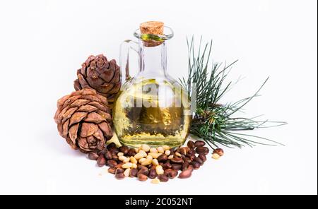 Isolieren, Pinienkerne mit einem Pinienkegel und eine Flasche mit Öl auf weißem Hintergrund Stockfoto