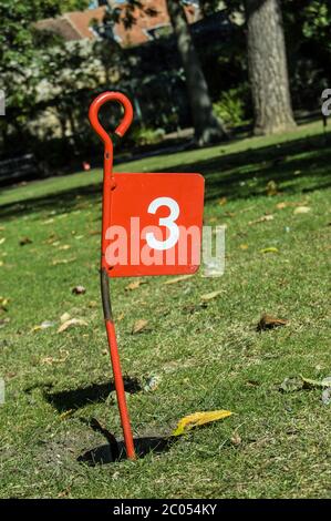 Ein rotes Metallfahnenschild am Golfplatz Nummer drei auf dem Minigolfplatz in Abbey Gardens, Bury St Edmunds, Suffolk. Stockfoto