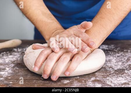 Hände einer unkenntlichen Frau, die auf einem Holztisch Brotknetmasse knetet, Konzept der gesunden Ernährung zu Hause Stockfoto