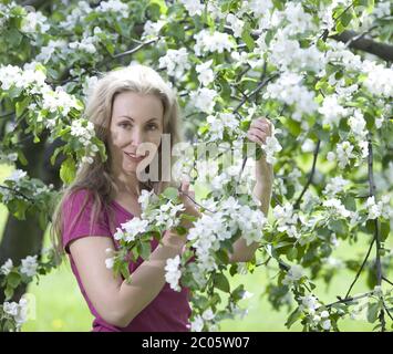 Frau stand in der Nähe des blühenden Apfelbaums Stockfoto