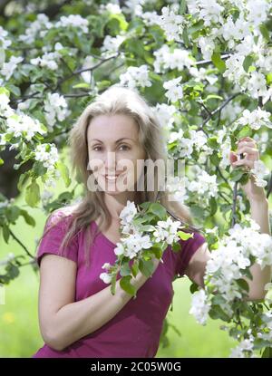 Frau stand in der Nähe des blühenden Apfelbaums. Stockfoto