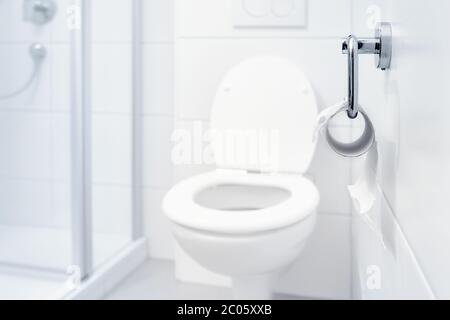 Nicht auf Lager, kein Toilettenpapier mehr. Letztes Stück Papier auf einer Rolle in einem sauberen und leeren weißen Badezimmer. Panik, Angst und weltweite Einkaufskrise. Stockfoto