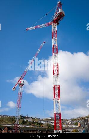 Riesige rot-weiße Krane auf einer Baustelle in Swansea, Wales, Vereinigtes Königreich. Stockfoto