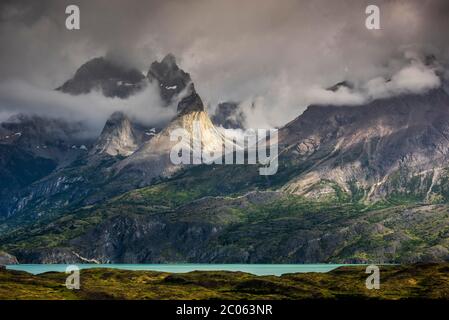 Blick über den Nordenskjöld See auf die Bergkette Cuernos del Paine in Wolken, Nationalpark Torres del Paine, Región de Magallanes y de la Antártica Stockfoto