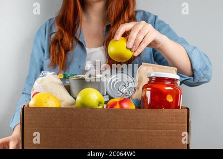 Frau, die eine Spendenbox mit Lebensmitteln verpackt. Freiwilligenprogramm Stockfoto