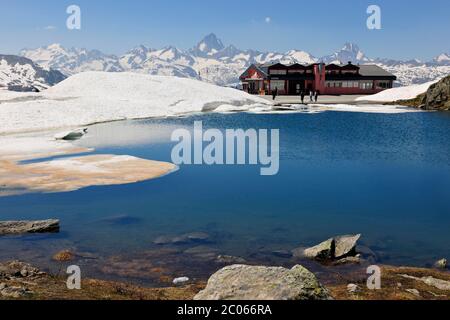 Pass Nufenenpass mit Restaurant, kleiner Bergsee, schneebedeckte Bergspitzen Pass Nufenenpass mit Schnee, Restaurant und kleiner Bergsee Stockfoto