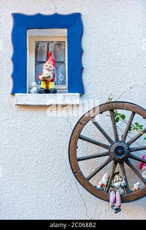 Gartenzwerge an einem kleinen Fenster und in einem hölzernen Wagenrad, Steinau an der Straße, Hessen, Deutschland Stockfoto