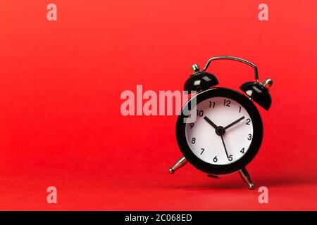 Schwarzer Vintage-Wecker, der auf den Boden fällt und einen farbigen Hintergrund hat Stockfoto