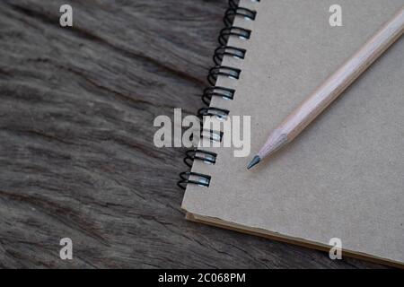 Bleistift auf Buchmockup auf dem alten Holzschreibtisch im Hintergrund, Flachlay Foto, Draufsicht Stockfoto