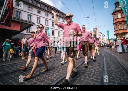 Die Menschen präsentieren das traditionelle Outfit mit typischen Bierkrügen aus der heimischen Brauerei Würzburger Hofbräu bei der Kiliani Sommerfestparade. Stockfoto