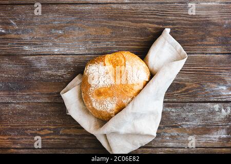 Ein Brötchen mit frisch gebackenem, heeastless Brot mit rustikalem Hintergrund. Das Konzept der hausgemachten Diät-Bäckerei ohne Hefe. Stockfoto