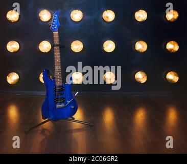 Musikkonzept. E-Gitarre steht auf dem Holzboden in der Nähe der Wand Stockfoto