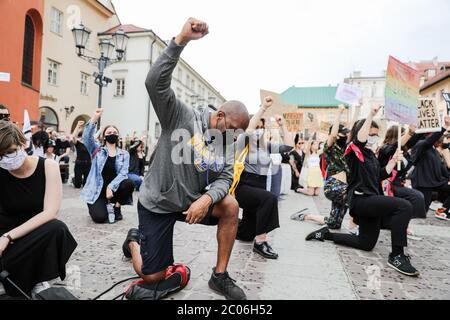 Ein afroamerikanischer Protestler kniet sich in medizinischen Masken nieder und hält seine Faust in der Luft während des "Black Lives Matter"-Protests in Krakau, der größten Cit Stockfoto