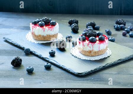 Köstlicher Erdbeerkäse auf schwarzem Teller mit frischen Blaubeeren im Hintergrund Stockfoto