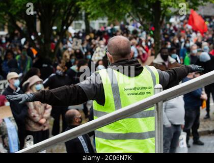 Newport, Wales, Großbritannien. Juni 2020. Ein Steward zeigt den Menschen, wie man sich in der Menge sozial distanziert. Hunderte von Menschen schlossen sich dem Protest nach dem Tod von George Floyd, einem 46-jährigen, afroamerikanischen Mann, der während einer Verhaftung durch die Minneapolis-Polizei für angeblich mit einer gefälschten Rechnung starb. Sein Tod hat weltweit riesige Proteste gegen Rassendiskriminierung ausgelöst. Kredit: Tracey Paddison/Alamy Live News Stockfoto