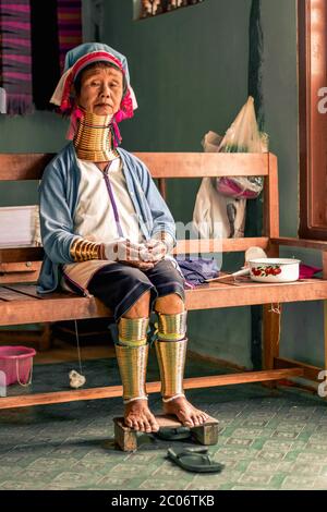 Frau mit langem Hals aus dem Kayan Stamm sitzt auf einer Bank am Inle Lake in Myanmar Burma Stockfoto