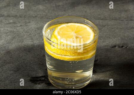 Erfrischendes Getränk aus kaltem Wasser mit Zitrone in einem transparenten Glas auf grauem Hintergrund Stockfoto