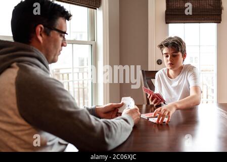 Der junge Mann und sein Vater spielen zusammen am Tisch Karten. Stockfoto