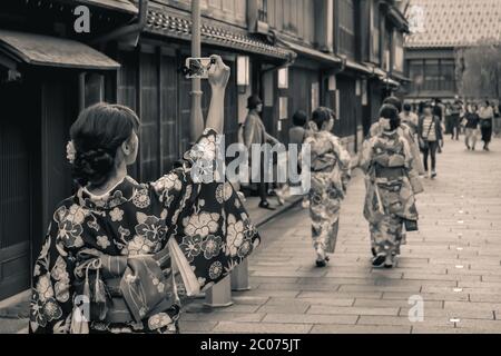 Japanische Mädchen in einem traditionellen Sommer Yukata ein Foto von ihren Freunden auf einer historischen Straße in Kanazawa Japan Stockfoto