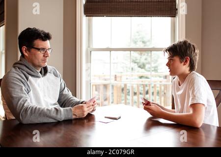 Der junge Mann und sein Vater spielen zusammen am Tisch Karten. Stockfoto