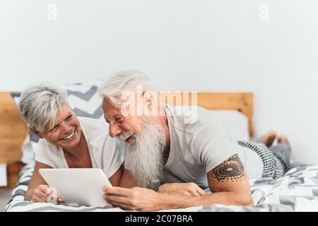 Happy Senior paar mit digitalen Tablet im Bett - ältere Menschen mit lustigen Bett Zeit zusammen Stockfoto