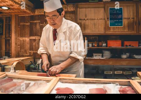 Sushi-Chefkoch bereitet auf dem Tsukiji-Fischmarkt in Tokio Japan frisches Thunfisch-Sashimi-Frühstück zu Stockfoto