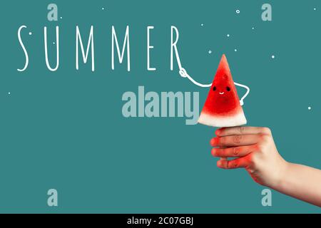Hand hält ein Stück Wassermelone auf einem Stock wie Eis auf einem grünen Hintergrund. Stockfoto
