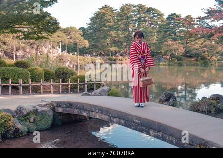 Nicht identifizierte japanische Gilr in einem rosa Kimono, die im Herbst auf einem Bergrücken im Kenrokuen-Garten in Kanazawa steht Stockfoto