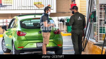 La Mexicana, Santa Fe, Mexiko-Stadt: 9. Juni 2020. Tankstellenmitarbeiter, der einem Benutzer eine Kreditkarte belastet. Mundschutz Stockfoto