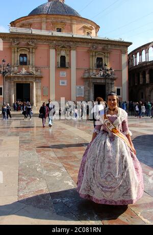 Junge Frau in traditionellem valencianischem Kleid vor der Basílica de la Virgen de los Desamparados (Basilika der Muttergottes der Vergessenen) Valencia Stockfoto