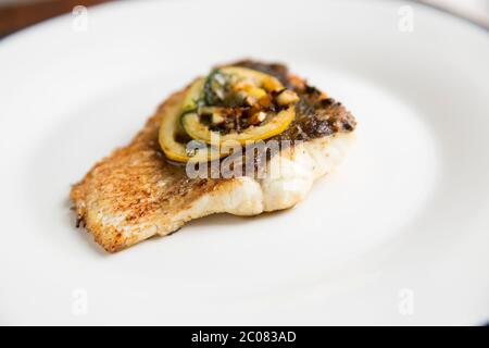 Ein gebratenes Filet aus einem Bass, Dicentrarchus labrax, das in der Nacht beim Strandfischen mit Rute und Linie gefangen wurde. Das Filet wurde in Olivenöl und gebraten Stockfoto